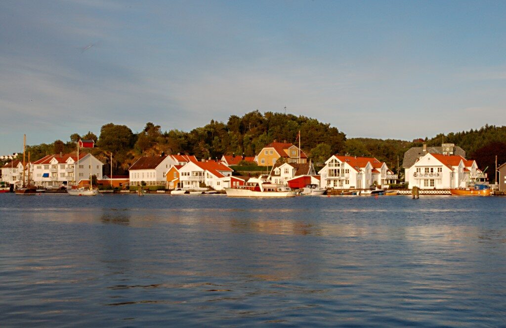 Hvite sørlandshus ved sjøen i kveldssol